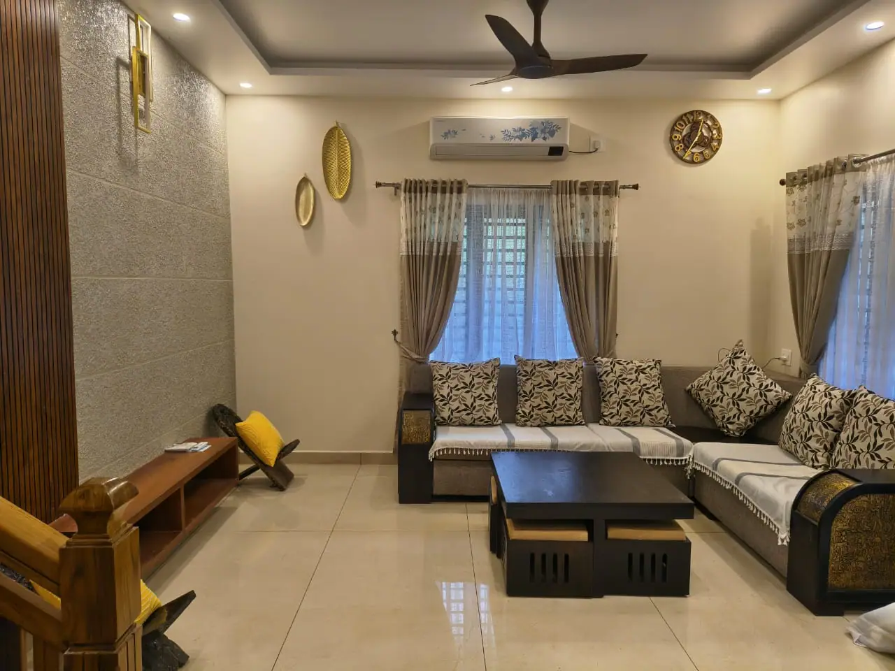 Living area at Nyra Thottam with an L-shaped sofa, wooden coffee table and warm ceiling lighting